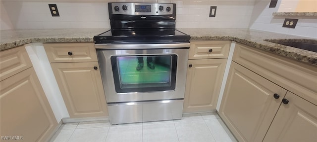 kitchen with electric stove, light tile patterned floors, decorative backsplash, and light stone countertops