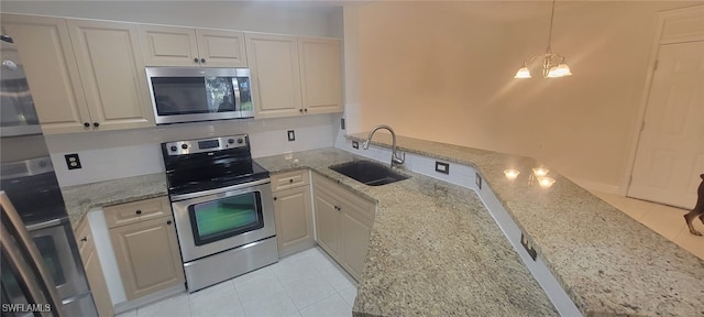 kitchen featuring decorative light fixtures, sink, white cabinets, stainless steel appliances, and light stone countertops