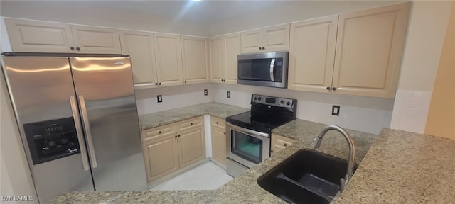 kitchen with sink, light tile patterned floors, light stone countertops, and appliances with stainless steel finishes