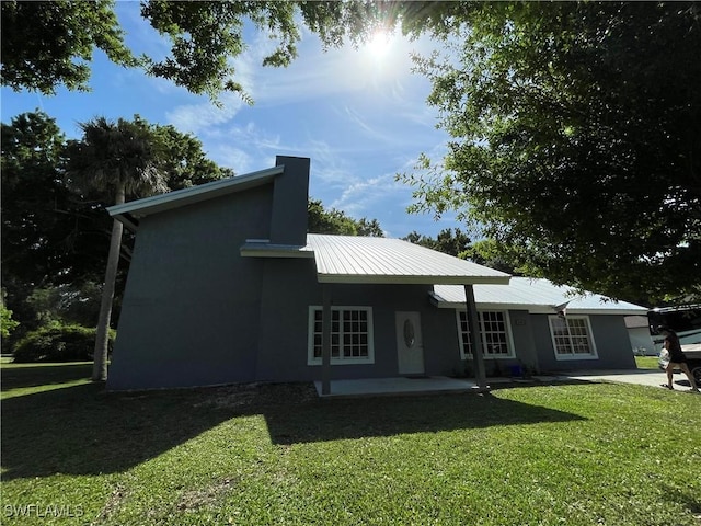 200 Ridgewood Ave, Clewiston, FL 33440 - rear view of property with a yard, metal roof, stucco siding, and a patio