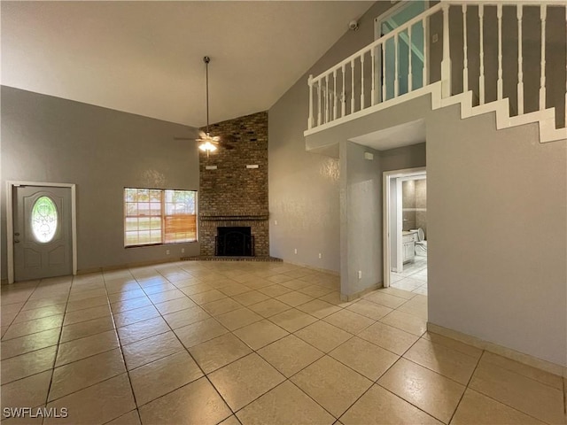 unfurnished living room with light tile patterned floors, high vaulted ceiling, a brick fireplace, and ceiling fan