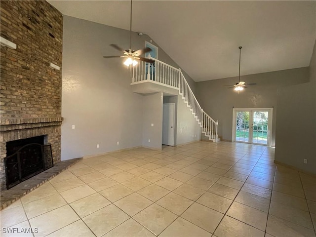 unfurnished living room with a brick fireplace, light tile patterned floors, high vaulted ceiling, and ceiling fan