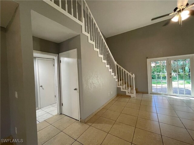 stairs featuring ceiling fan, tile patterned flooring, and a high ceiling