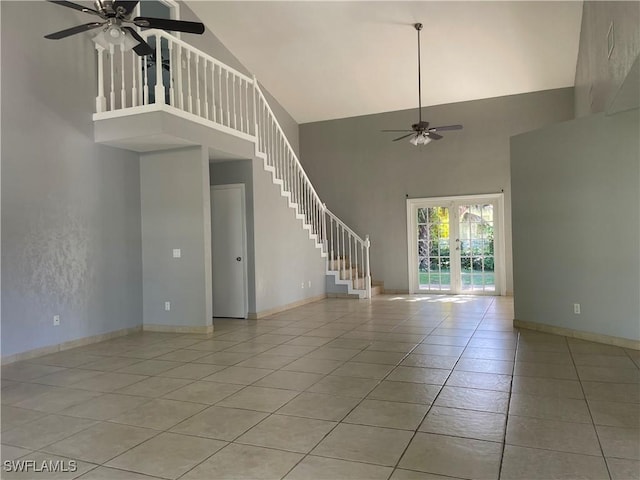 unfurnished living room featuring french doors, ceiling fan, a towering ceiling, and light tile patterned floors