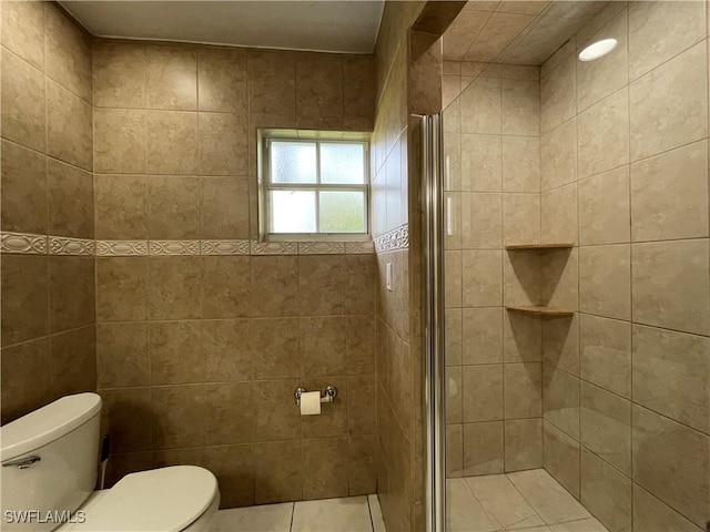 bathroom with toilet, a shower with shower door, and tile walls