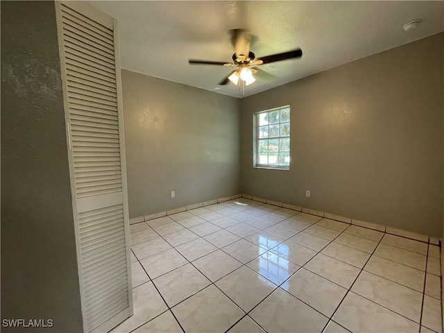 unfurnished bedroom with light tile patterned floors, a closet, and ceiling fan