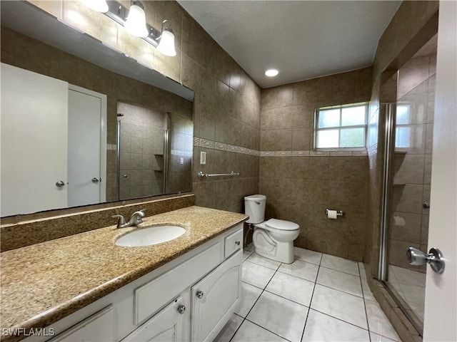 bathroom featuring tile walls, tile patterned flooring, vanity, toilet, and a shower with door