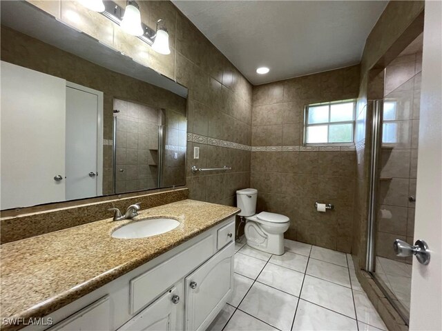 200 Ridgewood Ave, Clewiston, FL 33440 - full bathroom with tile walls, vanity, a stall shower, toilet, and tile patterned floors