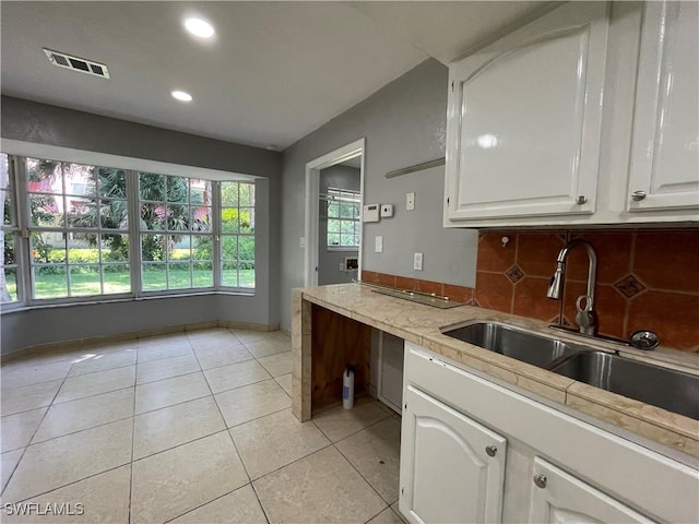 kitchen with white cabinetry, sink, decorative backsplash, and light tile patterned floors