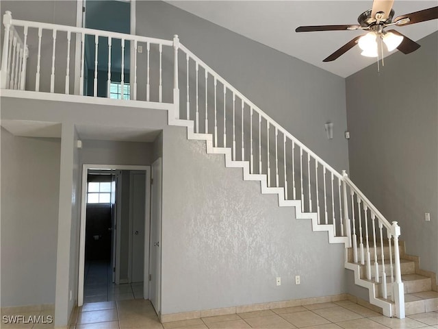 stairs featuring tile patterned floors, ceiling fan, and a high ceiling