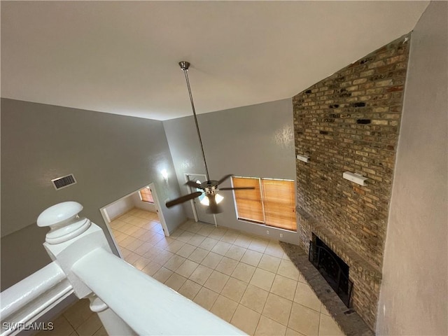 living room featuring vaulted ceiling, light tile patterned flooring, a fireplace, and ceiling fan