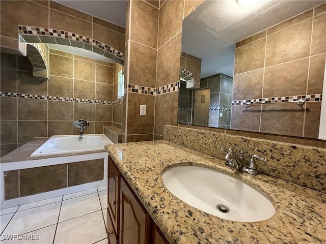 bathroom featuring tile patterned flooring, vanity, tiled tub, and tile walls