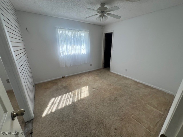 empty room featuring ceiling fan, light carpet, and a textured ceiling