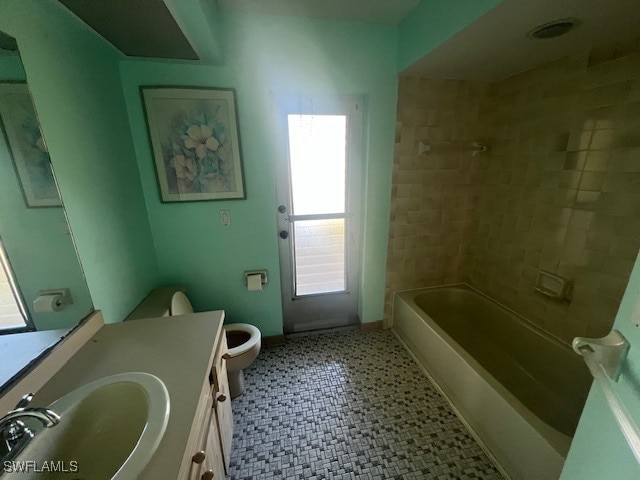 full bathroom with tiled shower / bath, vanity, and toilet