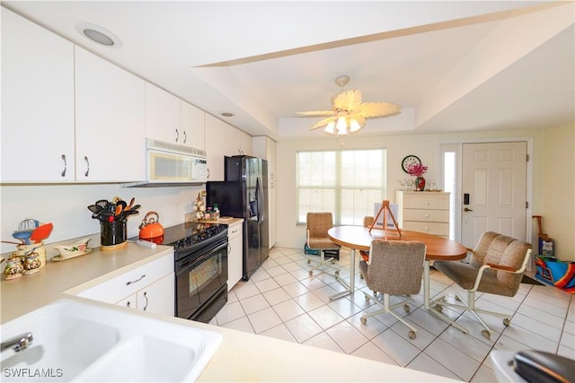 kitchen with light tile patterned floors, ceiling fan, a tray ceiling, black appliances, and white cabinets