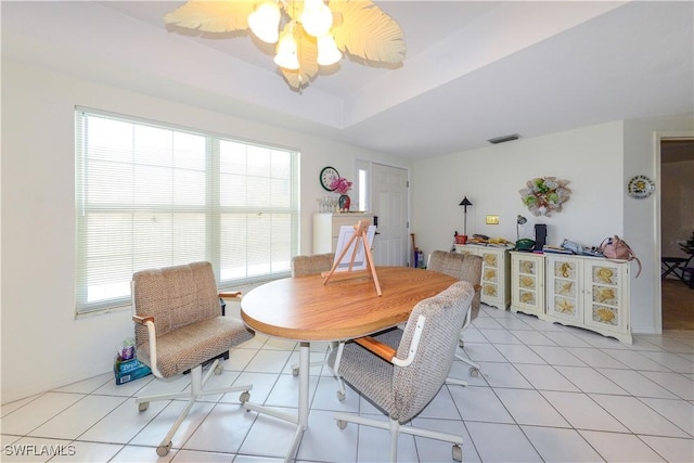 tiled dining room featuring ceiling fan and a tray ceiling