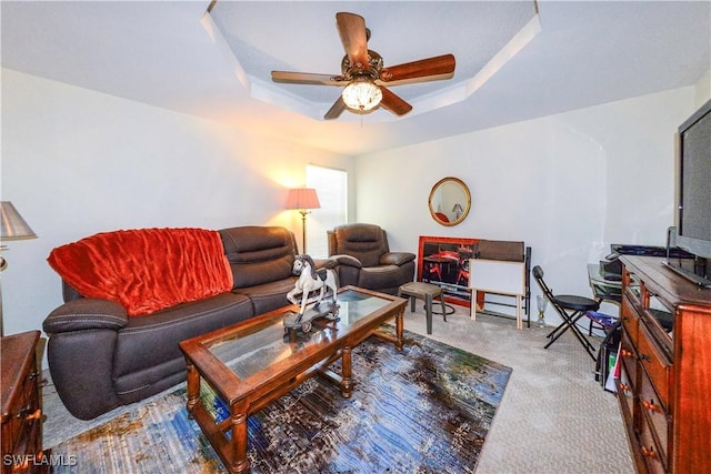 carpeted living room with a tray ceiling and ceiling fan