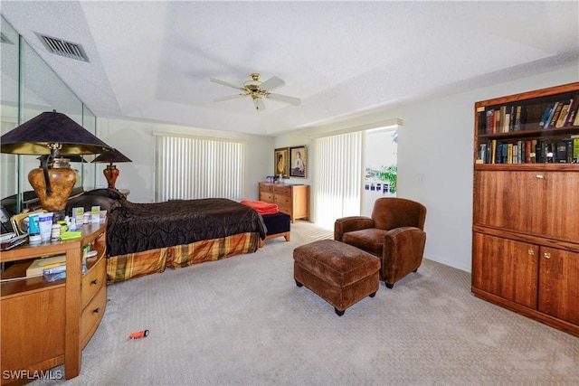 carpeted bedroom with a tray ceiling and ceiling fan