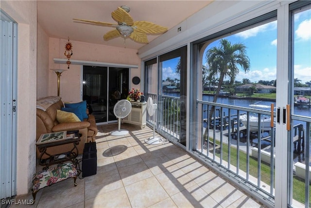 sunroom / solarium with ceiling fan and a water view