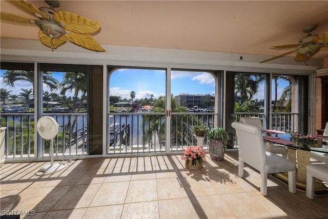 unfurnished sunroom featuring ceiling fan and a water view