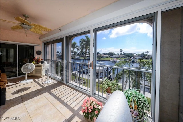 sunroom / solarium featuring a water view and ceiling fan