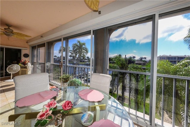 sunroom / solarium with ceiling fan and a water view