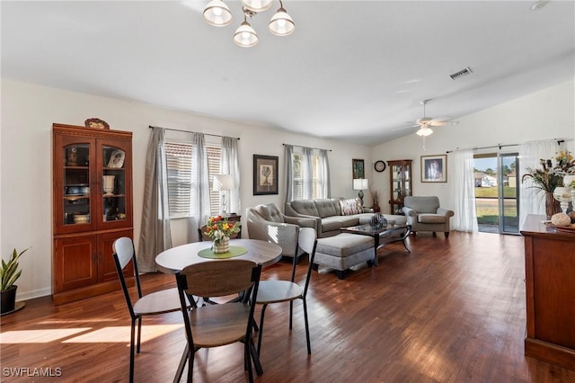 dining space featuring dark wood-type flooring, ceiling fan with notable chandelier, vaulted ceiling, and a wealth of natural light