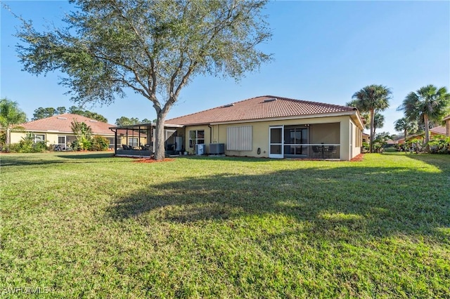 rear view of property featuring a sunroom, central AC, and a lawn