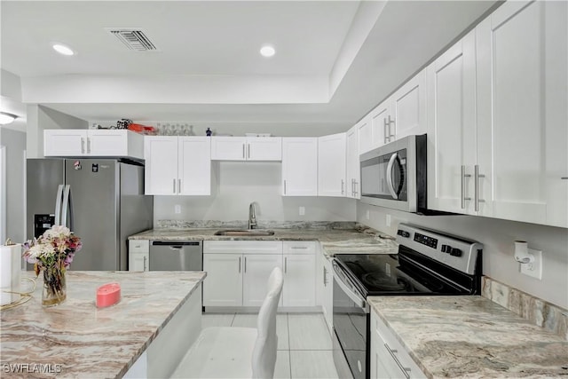 kitchen featuring light stone counters, sink, white cabinets, and appliances with stainless steel finishes