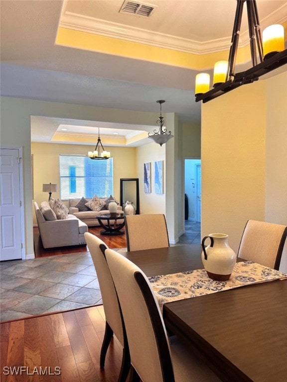 dining area with crown molding, a notable chandelier, a tray ceiling, and dark hardwood / wood-style floors