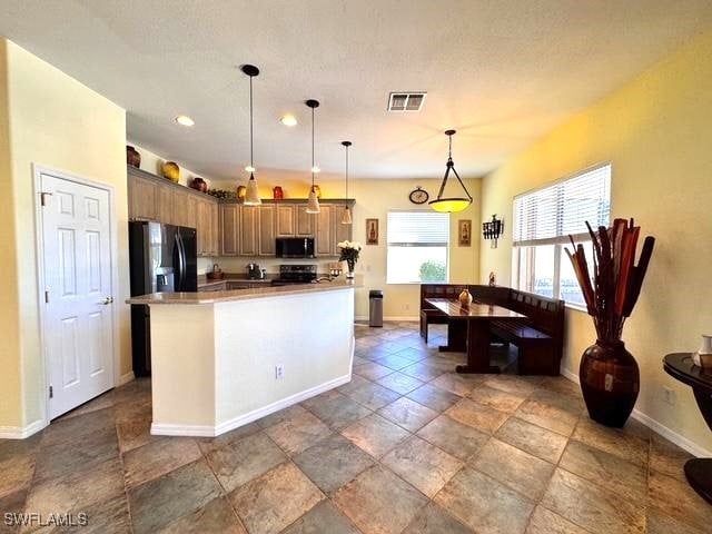 kitchen with range with electric cooktop, decorative light fixtures, stainless steel fridge with ice dispenser, and a center island with sink