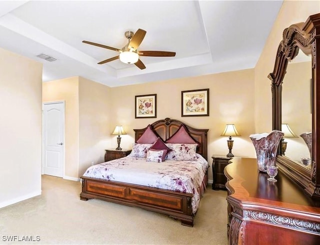 bedroom featuring ceiling fan, light colored carpet, and a raised ceiling