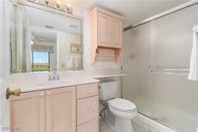 bathroom with vanity, ceiling fan, toilet, a shower with door, and tile patterned floors