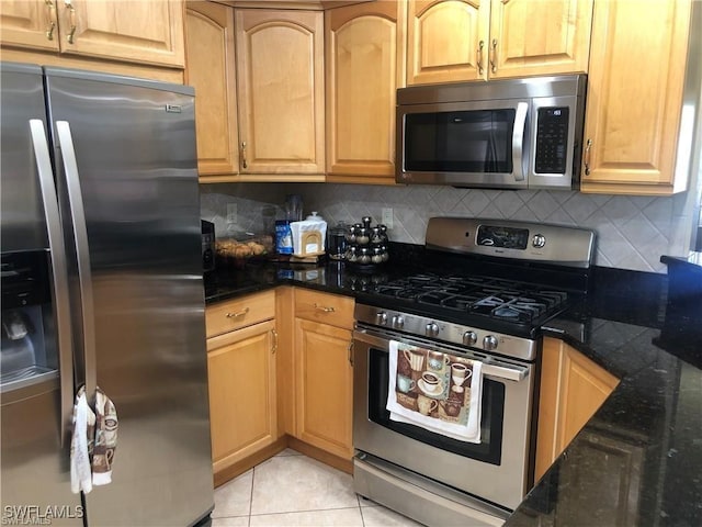 kitchen featuring backsplash, appliances with stainless steel finishes, light tile patterned floors, and dark stone counters