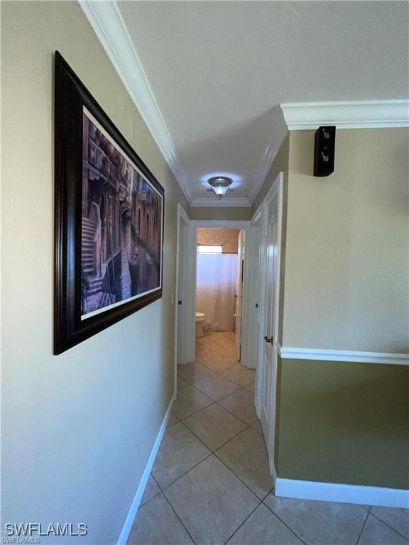 hallway featuring light tile patterned floors and ornamental molding