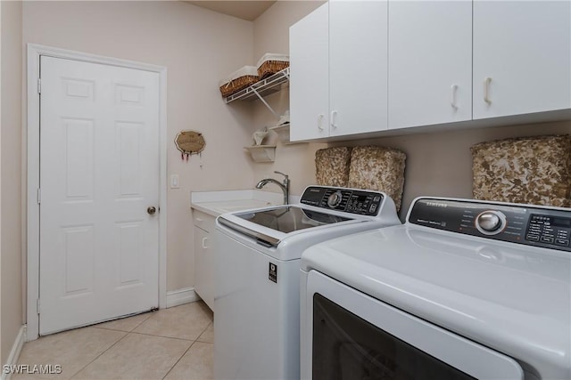 clothes washing area featuring cabinets, sink, washer and dryer, and light tile patterned floors