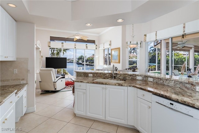 kitchen with white cabinetry, dark stone counters, white dishwasher, and sink