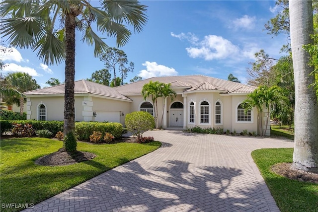 mediterranean / spanish-style home with a garage and a front yard