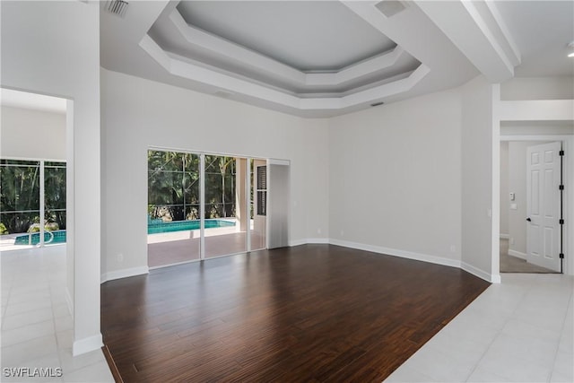 unfurnished living room with a towering ceiling, a tray ceiling, and hardwood / wood-style floors