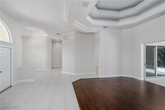 empty room featuring a raised ceiling and light hardwood / wood-style flooring