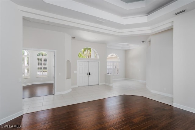 entrance foyer with a tray ceiling and light hardwood / wood-style flooring