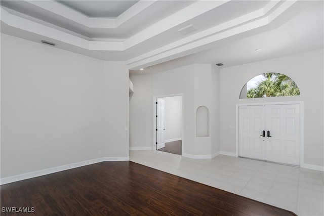 entrance foyer with hardwood / wood-style floors, a towering ceiling, and a raised ceiling