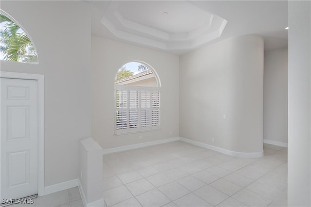 spare room featuring a tray ceiling and light tile patterned flooring