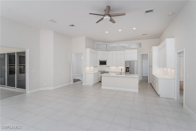 kitchen featuring stainless steel refrigerator with ice dispenser, sink, a center island with sink, white cabinets, and a high ceiling