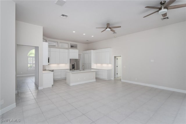 kitchen with stainless steel refrigerator with ice dispenser, a center island, white cabinets, and ceiling fan