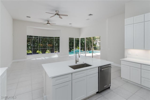 kitchen with sink, light tile patterned floors, a kitchen island with sink, white cabinets, and stainless steel dishwasher