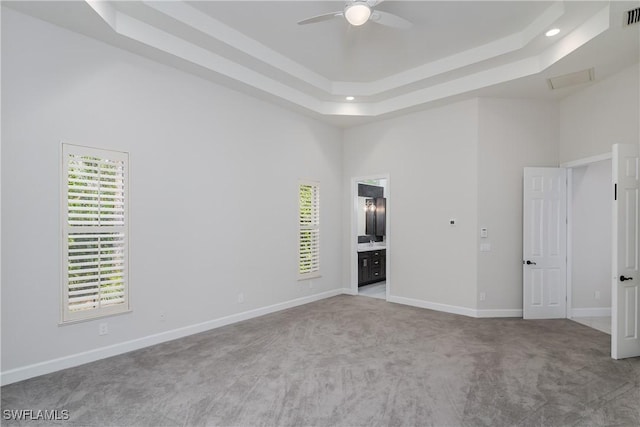 carpeted spare room featuring a tray ceiling, a towering ceiling, and ceiling fan