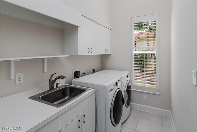 clothes washing area with light tile patterned flooring, cabinets, sink, and washing machine and clothes dryer