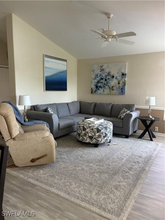 living room with ceiling fan, lofted ceiling, and wood-type flooring