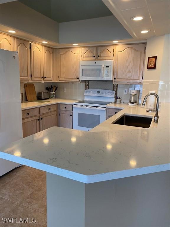 kitchen featuring white appliances, light brown cabinetry, and sink